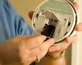 image of someone putting a battery in a smoke alarm